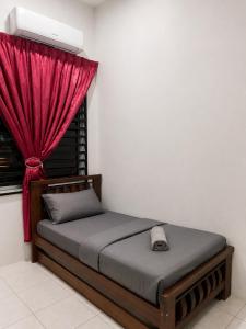 a bedroom with a bed with a red curtain at Casaria Homestay Cherating in Kampong Baharu Cherating