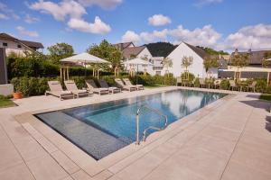 a swimming pool in a yard with chairs and a house at Weingut und Gästehaus Apel in Nittel