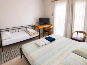 ein Schlafzimmer mit zwei Betten, einem Schreibtisch und einem Fernseher in der Unterkunft Elias Appartment in Volos