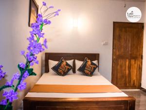 a bedroom with a bed with pillows and purple flowers at Lake View Dambulla in Dambulla