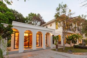 an exterior view of a white house with large windows at Kaysorn Siri in Ban Kham Kom