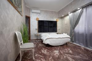 a bedroom with a large white bed and a chair at Casa Romana in Tor Vergata