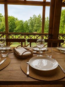 a wooden table with a plate and wine glasses on it at Medaus slėnis in Šilinė