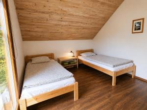 two beds in a room with wooden ceilings at Medaus slėnis in Šilinė