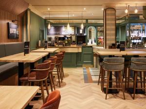 a restaurant with wooden tables and chairs and a bar at Mercure Northampton in Northampton