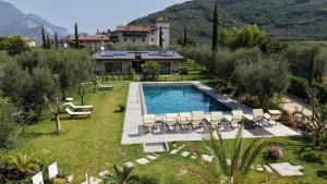 a pool with chairs and a house in the background at Oliveto Apartments in Riva del Garda
