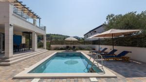 a swimming pool with chairs and an umbrella next to a house at Villa Olea by Villas Guide in Blace