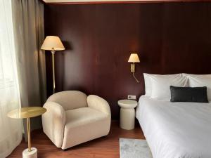 a bedroom with a bed and a chair and a lamp at Hotel Kalliohovi - ilmastoidut huoneet - in Rauma