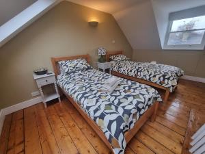 two beds in a room with wooden floors at Central Cambridge -comfortable Victorian Terrace in Cambridge
