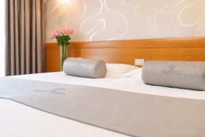 Twee kussens op een bed met een vaas bloemen. bij Hotel Venko in Dobrovo +28 foto's