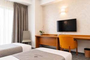 een hotelkamer met een bureau en een televisie bij Hotel Venko in Dobrovo