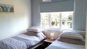 two beds in a room with a window at Hydaway in Bacton