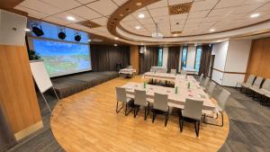 een vergaderruimte met tafels en stoelen en een groot scherm bij Hotel Venko in Dobrovo