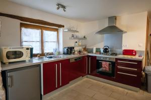 a kitchen with red cabinets and a microwave at La Grue Gites in Mons