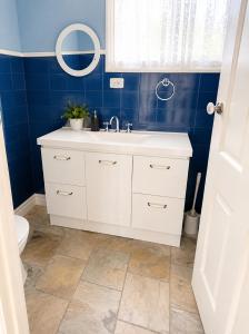 a bathroom with a white sink and a blue wall at Spacious Frankston Retreat in Frankston +16 photos