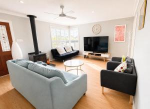a living room with two couches and a flat screen tv at Spacious Frankston Retreat in Frankston