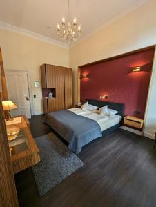 a bedroom with a large bed and a red wall at Weinhotel St. Stephanus in Zeltingen-Rachtig