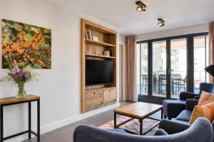 a living room with a flat screen tv and blue chairs at Ferienwohnung Strandperle in der Villa Martha Binz in Binz