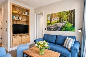 a living room with a blue couch and a tv at Ferienwohnung Sandbank in der Villa Martha Binz in Binz