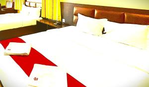 a bedroom with two beds with white sheets and a red headboard at The B And D Hotel in Guwahati