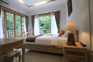 una camera con letto, scrivania e finestre di Gading Homestay Ubud ad Ubud