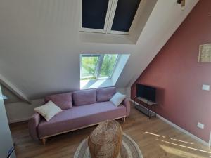a living room with a purple couch and a window at La maison des Hirondelles 2 in Fort-Mahon-Plage