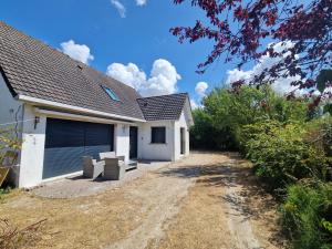 a white house with a garage and a dirt road at La maison des Hirondelles 2 in Fort-Mahon-Plage