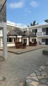a patio with tables and umbrellas in front of a building at Spice Garden Lodge B&B in Zanzibar City