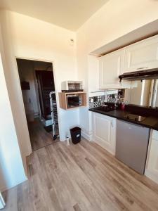 a kitchen with white cabinets and a wooden floor at Le Petit Condette in Condette