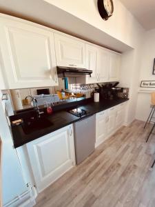 a kitchen with white cabinets and black counter tops at Le Petit Condette in Condette