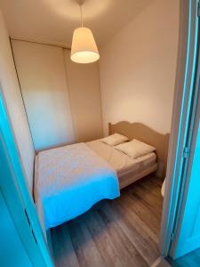 a small bedroom with a bed and a light at Le Petit Condette in Condette
