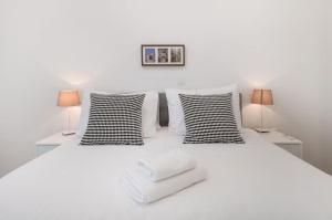 a white bed with three pillows and two lamps at Modern Penthouse Split with Jacuzzi & Terrace in Split +23 photos