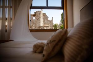 a teddy bear sitting on a bed in front of a window at O Recuncho do Castelo in Ribadavia