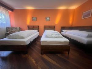 two beds in a room with orange walls at Hotel Waldblick BSR Garten mit Pavillons im Schwarzwald, ideal für Paare, Familien, Hunde in Donaueschingen