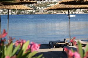 a beach with tables and umbrellas and a body of water at Costa Farilya Special Class Hotel Bodrum in Gundogan