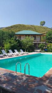 a swimming pool with lounge chairs and a house at Rati's Oda in Aspindza