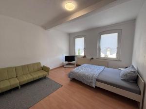 a bedroom with a bed and a couch and two windows at Comfortable and functional apartment in Kretzschau