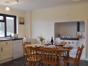 a kitchen with a wooden table and chairs in a room at Pengelli Cottage in Eglwyswrw