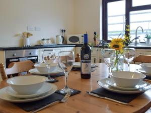 a table with a bottle of wine and glasses on it at Pengelli Cottage in Eglwyswrw