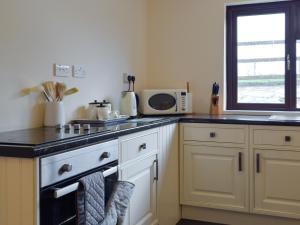 a kitchen with white cabinets and a stove top oven at Pengelli Cottage in Eglwyswrw +12 photos