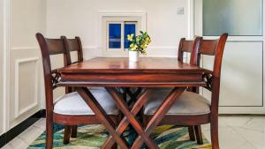a wooden table with four chairs and a vase with flowers at City Getaway Apartments in Zanzibar City
