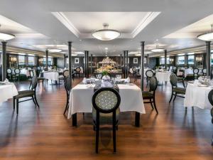 a dining room with white tables and chairs at Mövenpick MS Sunray in Luxor