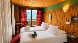 a room with two beds and a window at Plein Ciel - Hôtel d'altitude à 1800m in Champéry