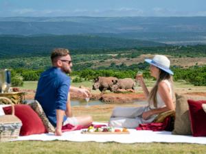 a man and woman sitting on a picnic blanket with elephants in the background at Founders Lodge by Mantis in Paterson