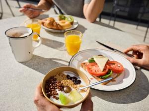 a person holding a bowl of food on a table at ibis Madrid Norte Las Tablas in Madrid