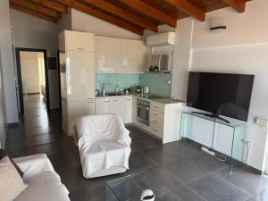 a kitchen with white cabinets and a tv in a room at Korelis Apartments in Agia Anna