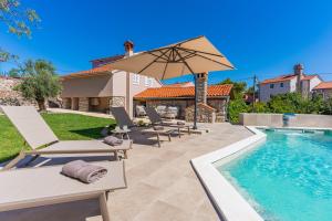 a pool with chairs and an umbrella next to a house at Villa Loznati in Cres
