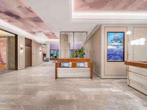a lobby of a building with a desk in the middle at Mercure Qingdao May Fourth Square in Qingdao