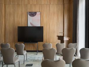 a room with a flat screen tv and chairs at Ibis Tashkent Index in Tashkent