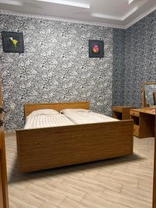 a bedroom with a wooden bed in front of a wall at Edle Tropfen in Tqibuli